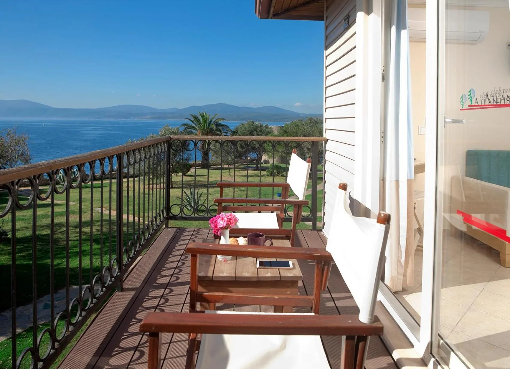 Une terrasse avec mobilier en bois offre une vue sur la mer et les montagnes.