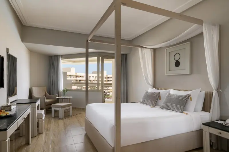 Une chambre lumineuse avec un grand lit à baldaquin et une vue sur la mer.