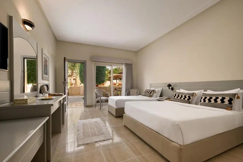 Chambre lumineuse avec deux lits simples et une vue sur la végétation.