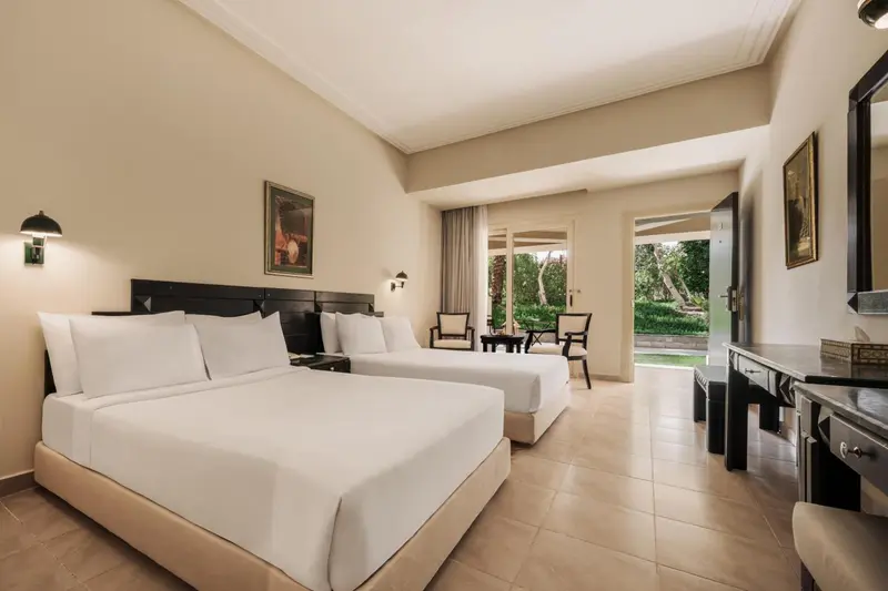 Une chambre lumineuse avec deux lits simples et un accès à une terrasse.