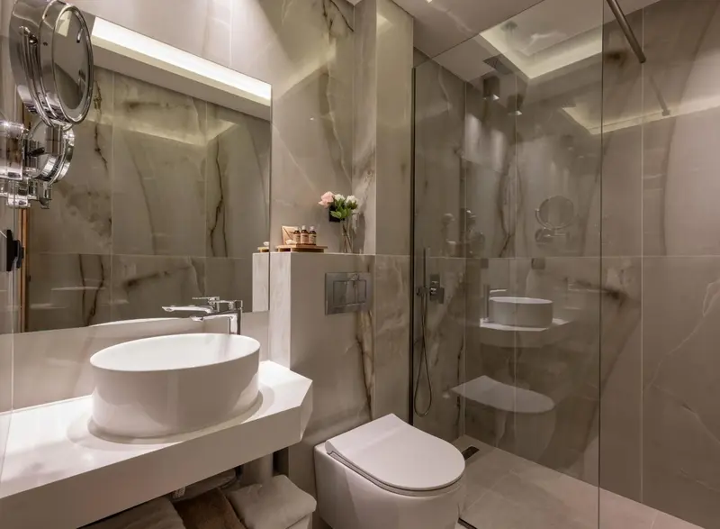 Une salle de bain moderne avec douche à l'italienne et vasque blanche.