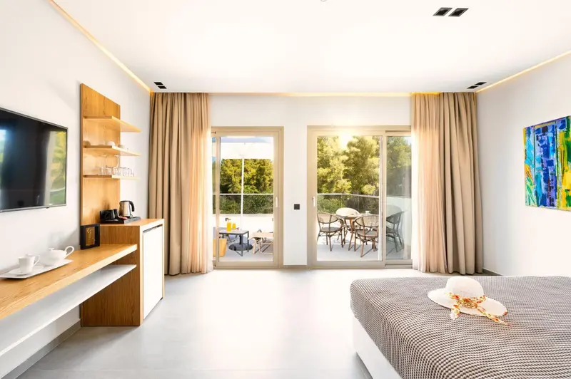 Chambre lumineuse avec un bureau et un accès à une terrasse.