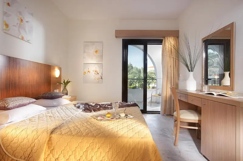 Chambre lumineuse avec un lit fait et un bureau en bois.