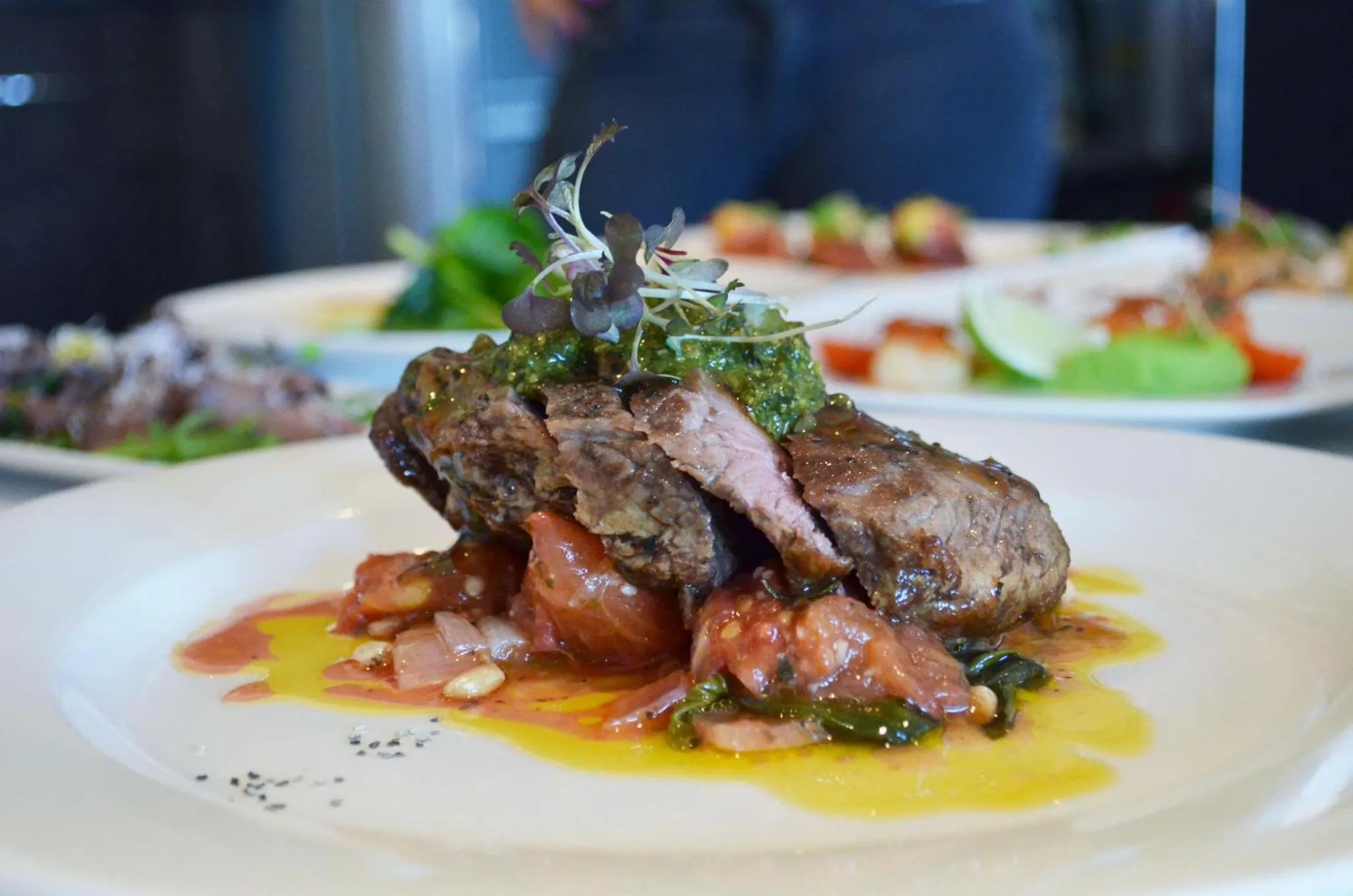 Assiette de viande grillée accompagnée d'une sauce colorée et de légumes.