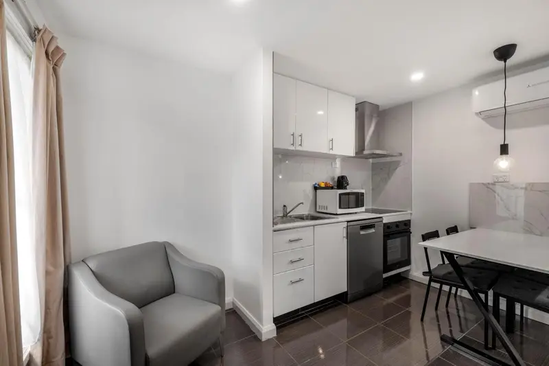 Une cuisine moderne s'ouvre sur un coin repas avec une chaise et un canapé.