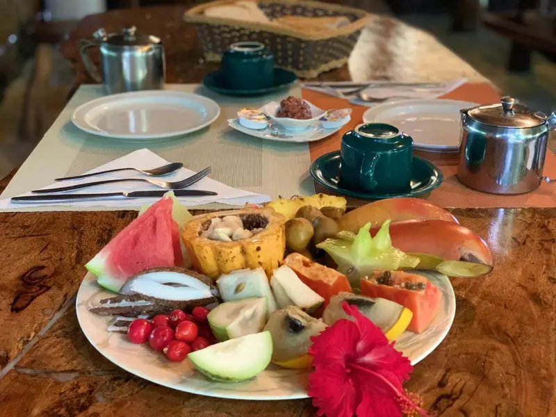 Une table est dressée avec un copieux petit-déjeuner composé de fruits frais, de viennoiseries et de boissons.
