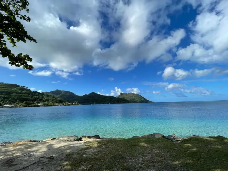 Ciel bleu nuageux au-dessus d'une côte rocheuse et d'une mer turquoise.
