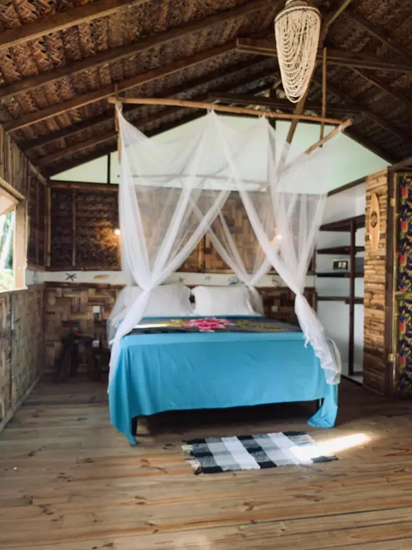 Une chambre avec un lit recouvert d'une moustiquaire et d'une couverture bleue.