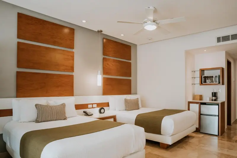 Chambre lumineuse avec deux lits simples et une décoration murale en bois.