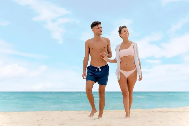 Un couple se promène sur une plage de sable fin, face à la mer.
