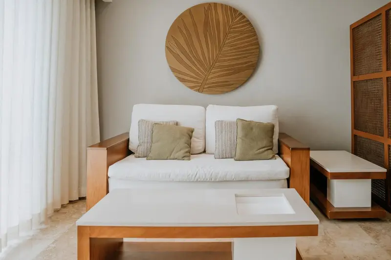 Un canapé blanc et des coussins verts se trouvent devant une décoration murale en bois.