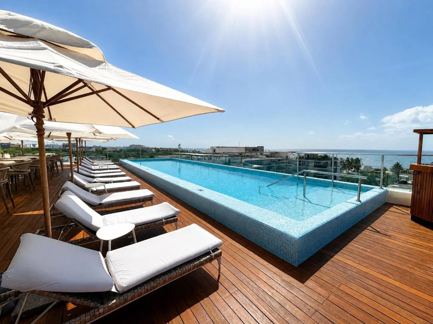 Terrasse avec transats et piscine à débordement offrant une vue sur la mer.
