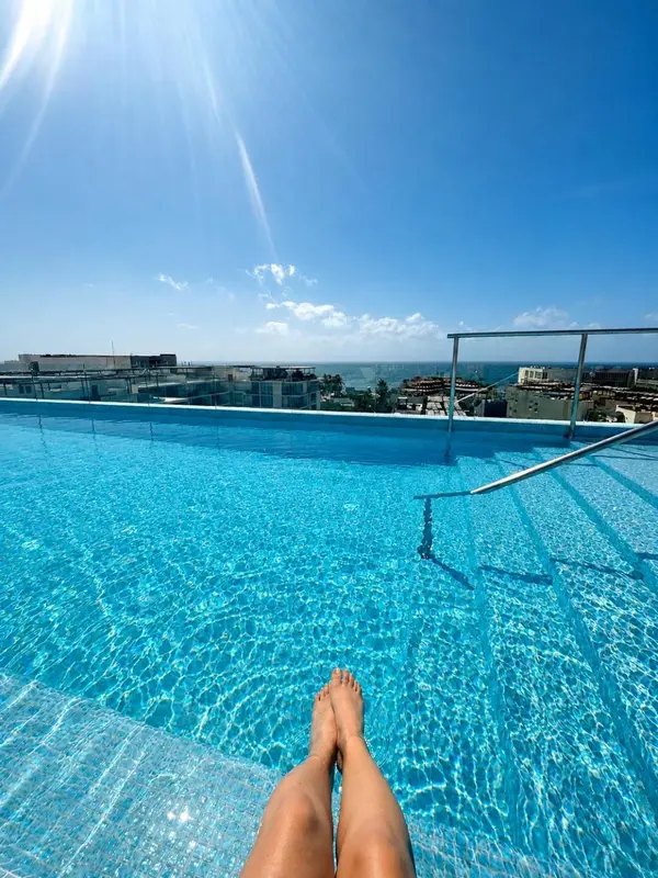 Pieds en suspension au bord d'une piscine à débordement avec vue sur la mer.