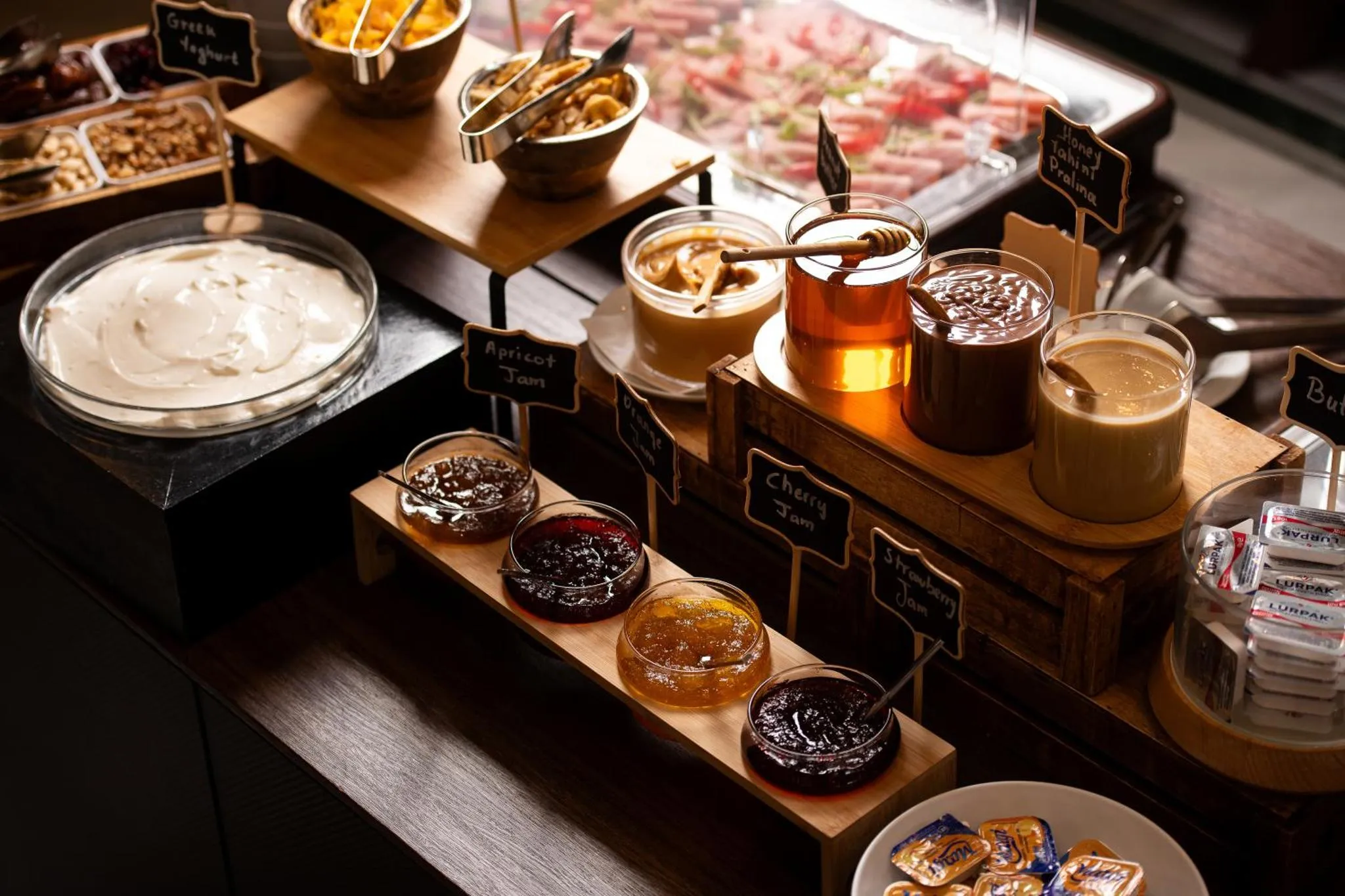 Présentation de confitures, de yaourts et de miels sur un buffet.