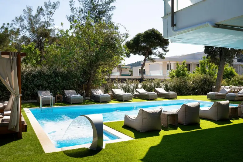 Transats et fauteuils de jardin bordent une piscine rectangulaire à débordement.
