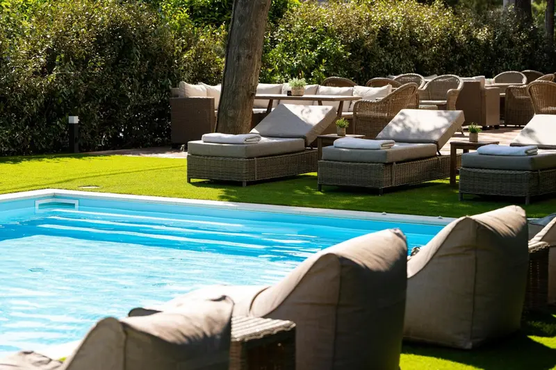 Mobilier de jardin confortable au bord d'une piscine ensoleillée.