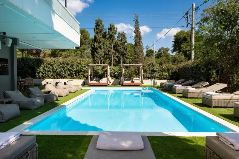 Une piscine rectangulaire bordée de chaises longues et de gazebos.