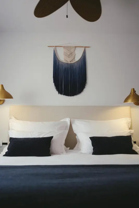 Un lit avec des oreillers blancs et des coussins noirs dans une chambre.
