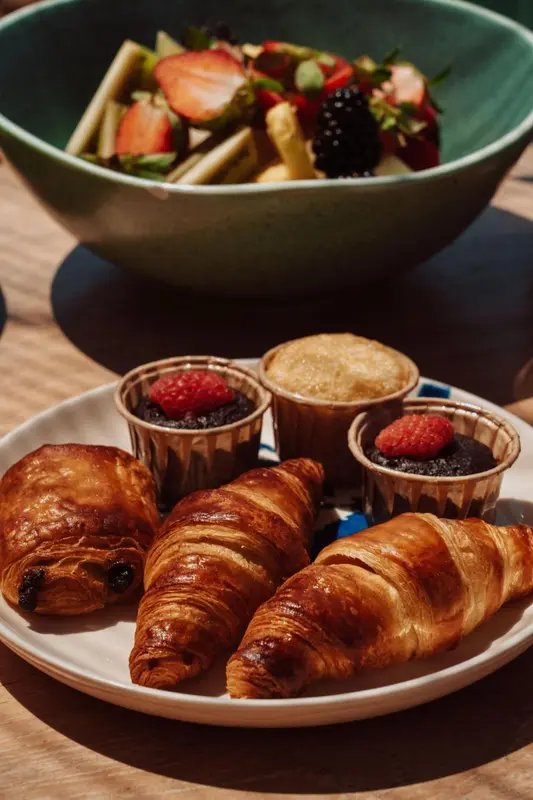 Assortiment de viennoiseries et de fruits frais présentés sur une table.
