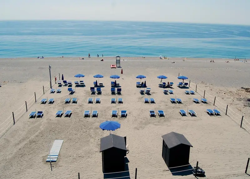 Vue aérienne d'une plage aménagée avec des parasols et des transats.