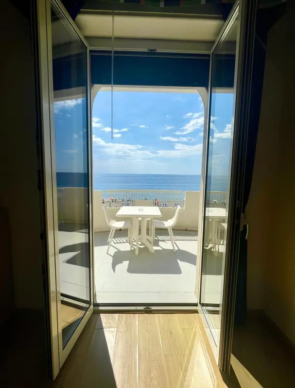 Vue sur la mer depuis une terrasse ensoleillée avec mobilier de jardin.