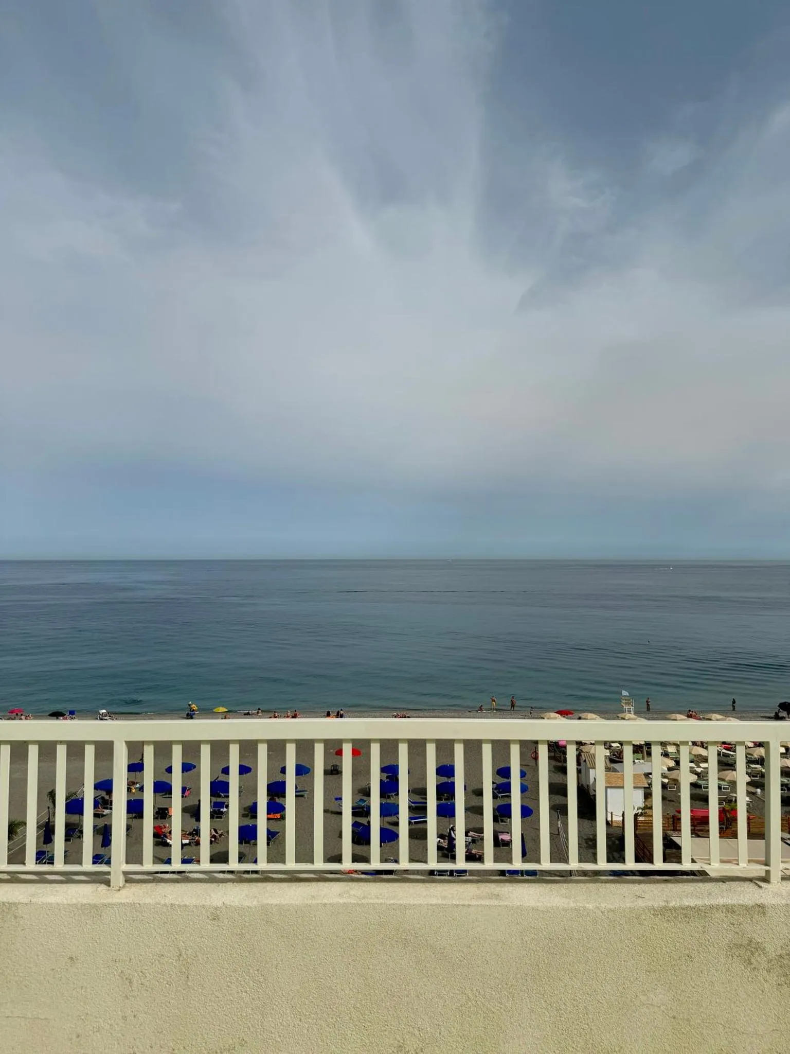 Vue sur la mer depuis une terrasse avec des transats bleus.