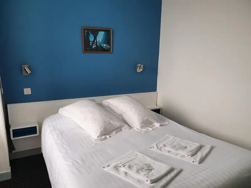 Une chambre lumineuse avec un lit double et une décoration murale.