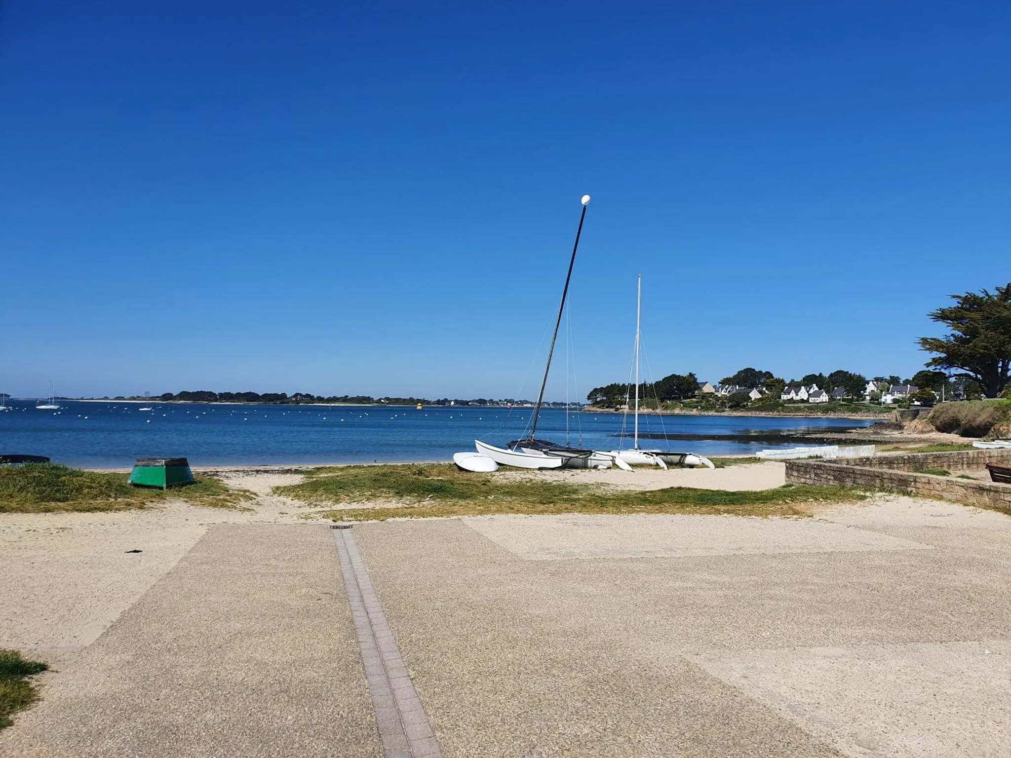 Plage de sable avec quelques embarcations à terre et une vue sur la mer.
