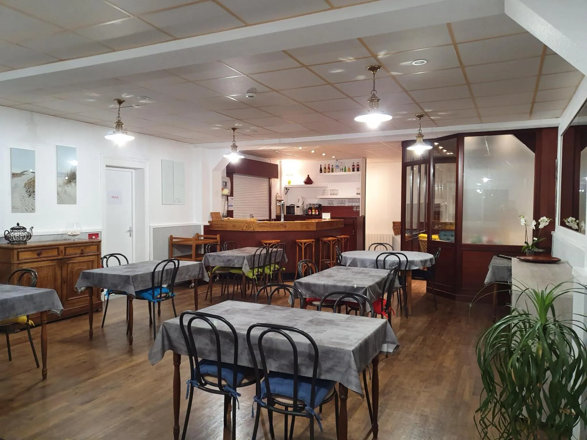 Une salle lumineuse avec des tables nappées et un comptoir de boissons.