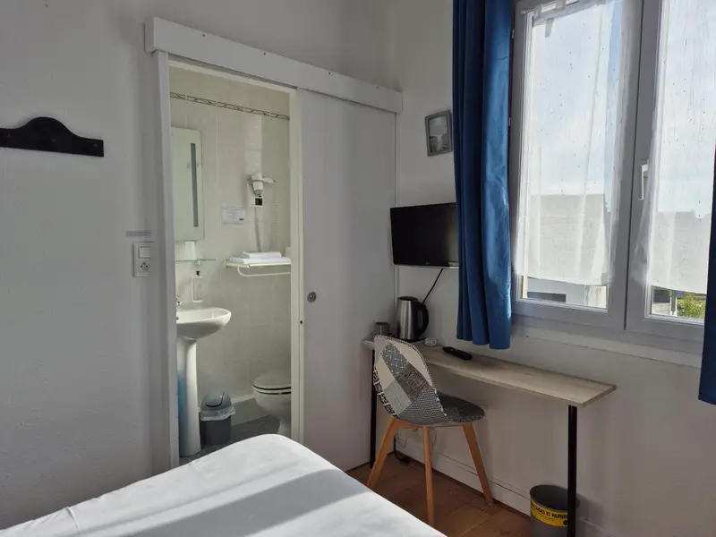 Une chambre lumineuse avec un bureau et une salle de bain attenante.