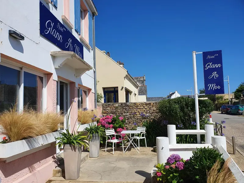 Façade d'un bâtiment rose et blanc avec des fleurs et des arbustes devant.