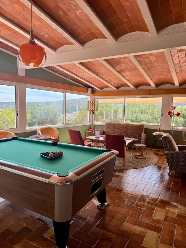 Une salle de jeux lumineuse avec un billard et des fauteuils confortables offre une vue sur le paysage.