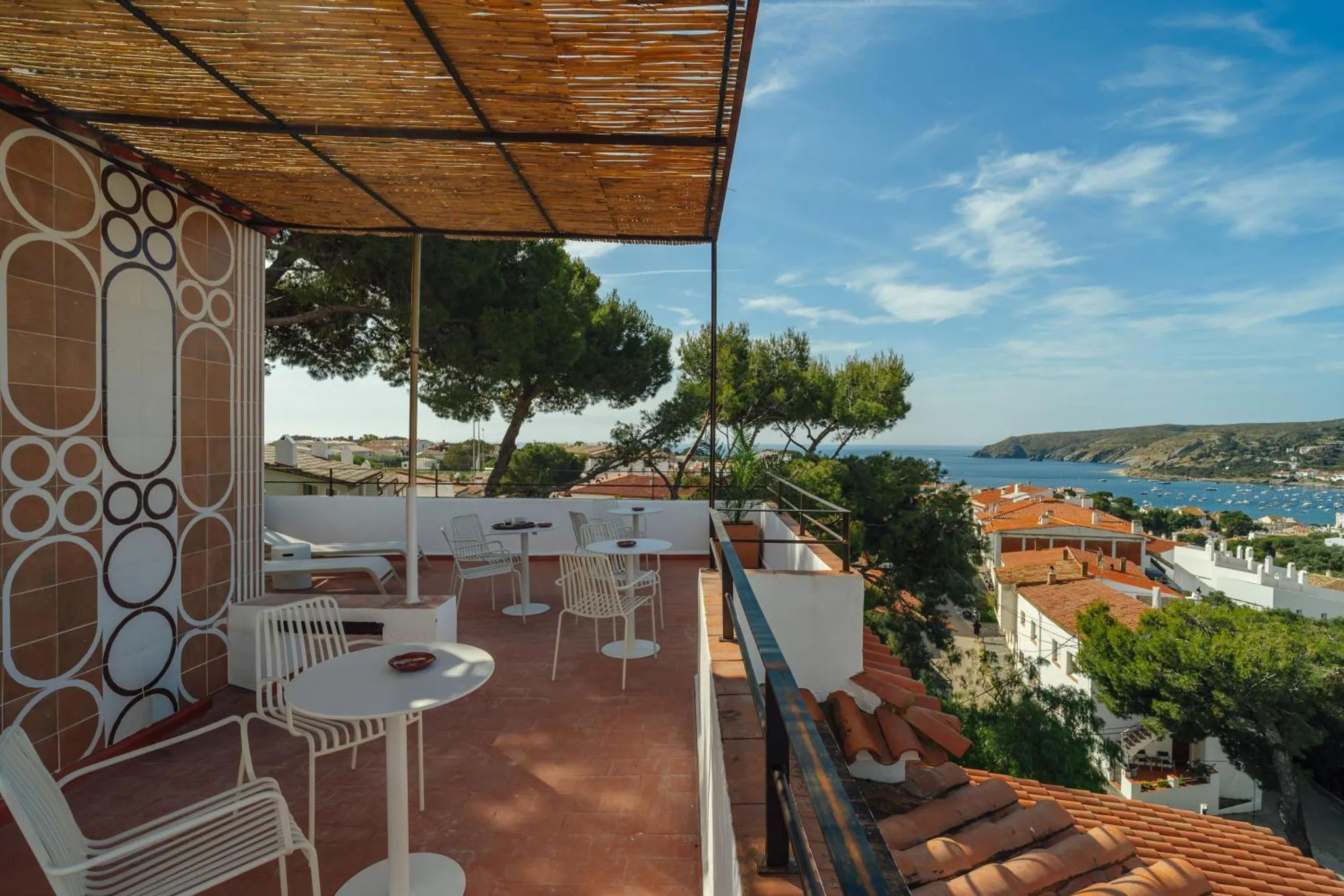 Terrasse ombragée avec mobilier blanc offrant une vue sur la mer et les environs.