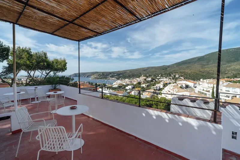 Terrasse avec mobilier blanc offrant une vue sur la mer et les collines.