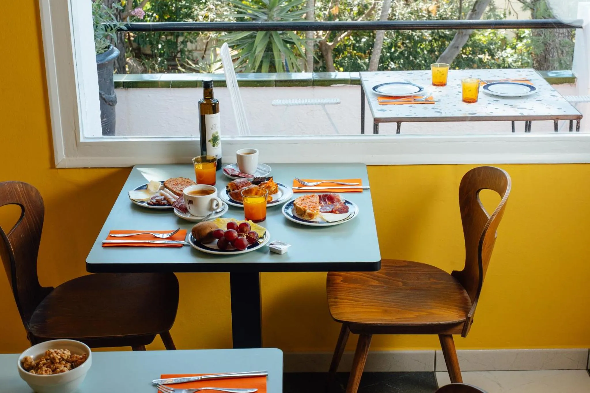 Une table est dressée pour le petit-déjeuner avec des viennoiseries et des boissons.