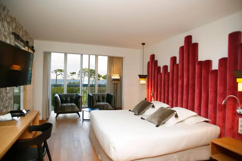 Une chambre lumineuse avec un grand lit et un coin salon donnant sur la mer.