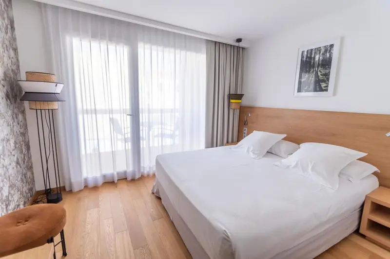 Une chambre lumineuse avec un grand lit et un accès à une terrasse.