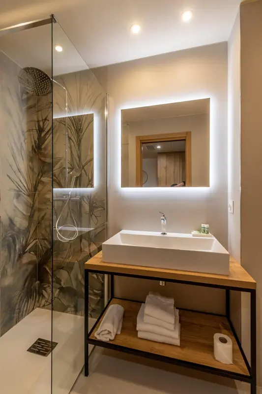 Une salle de bain moderne avec une douche à l'italienne et un grand miroir éclairé.