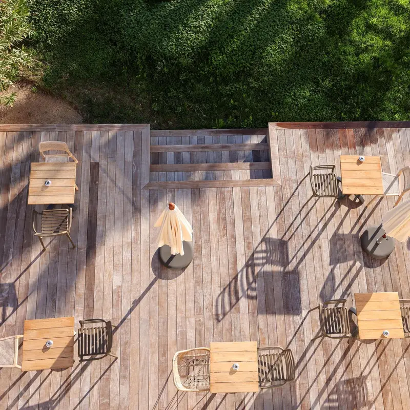 Terrasse en bois avec tables et chaises à l'ombre de parasols.
