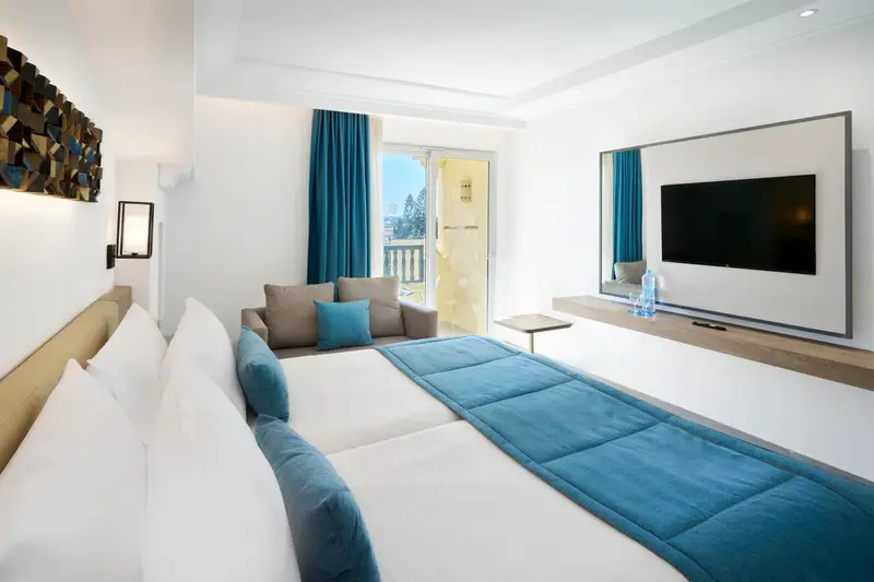 Une chambre lumineuse avec un canapé et un accès à un balcon.