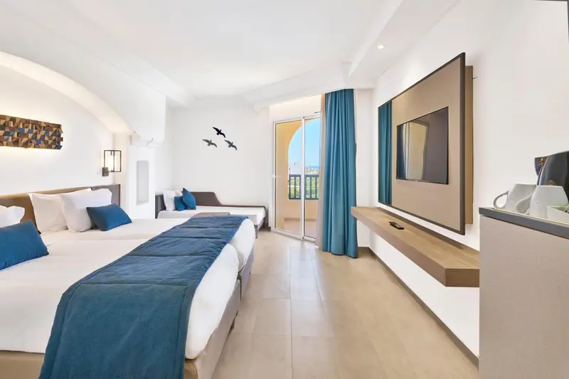 Une chambre lumineuse avec deux lits simples et un accès à un balcon.