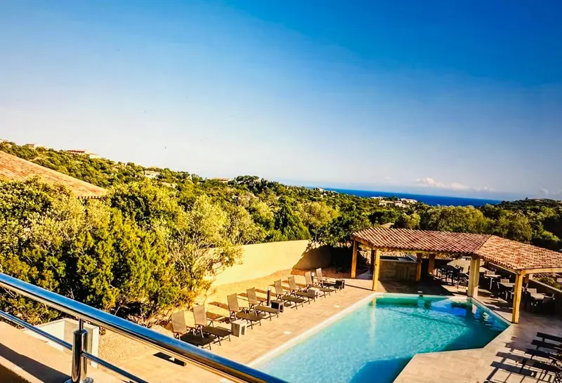 Terrasse avec piscine et vue sur la végétation et la mer.