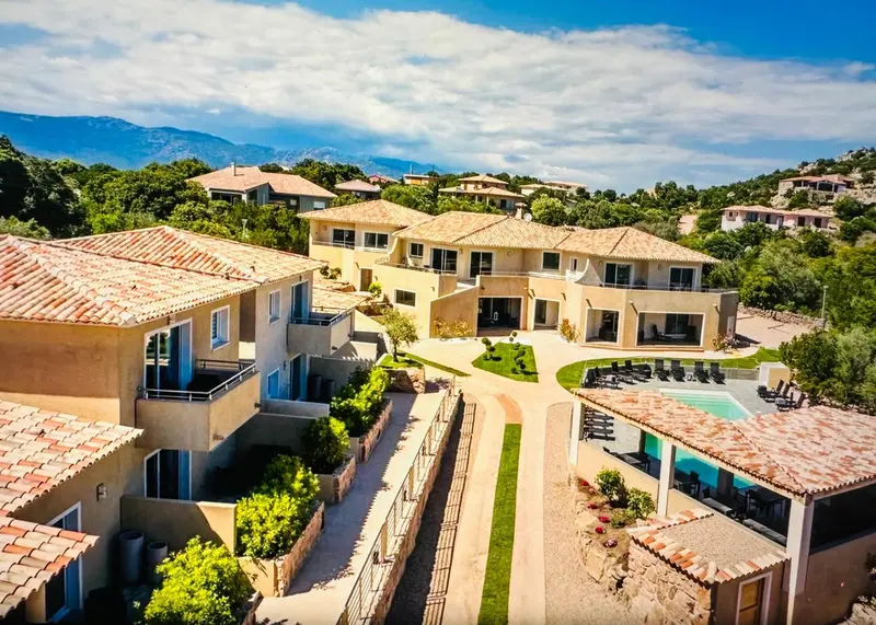 Vue aérienne d'un complexe hôtelier avec piscine et végétation luxuriante.