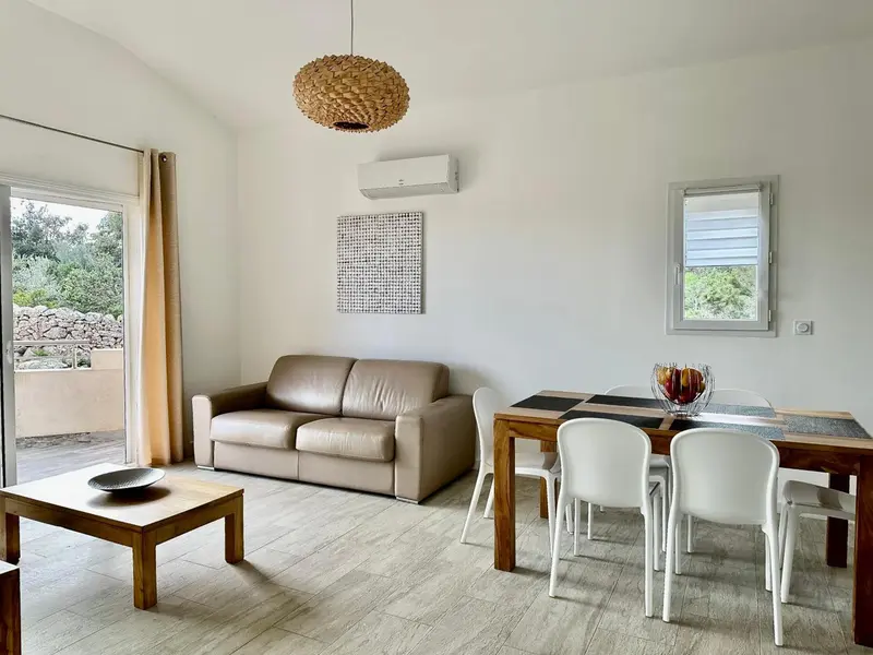 Espace de vie lumineux avec canapé et table à manger en bois.