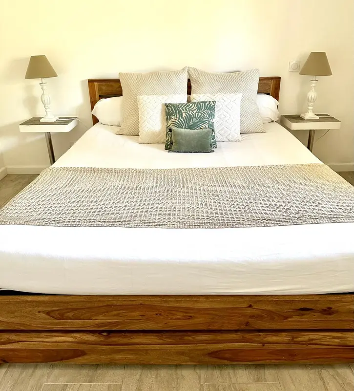 Un lit double avec une couette blanche et des oreillers décoratifs dans une chambre lumineuse.