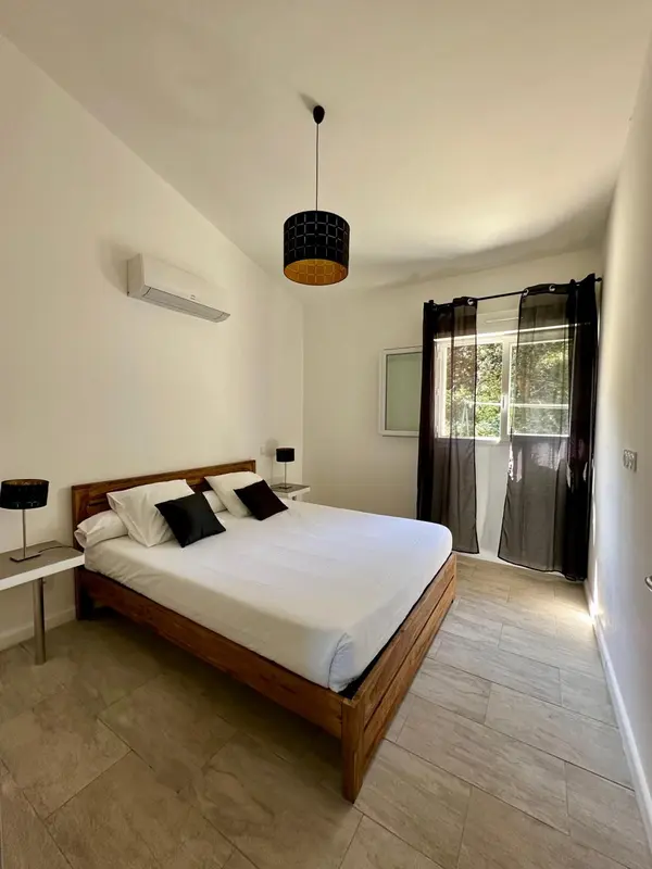 Une chambre lumineuse avec un lit double et une fenêtre.