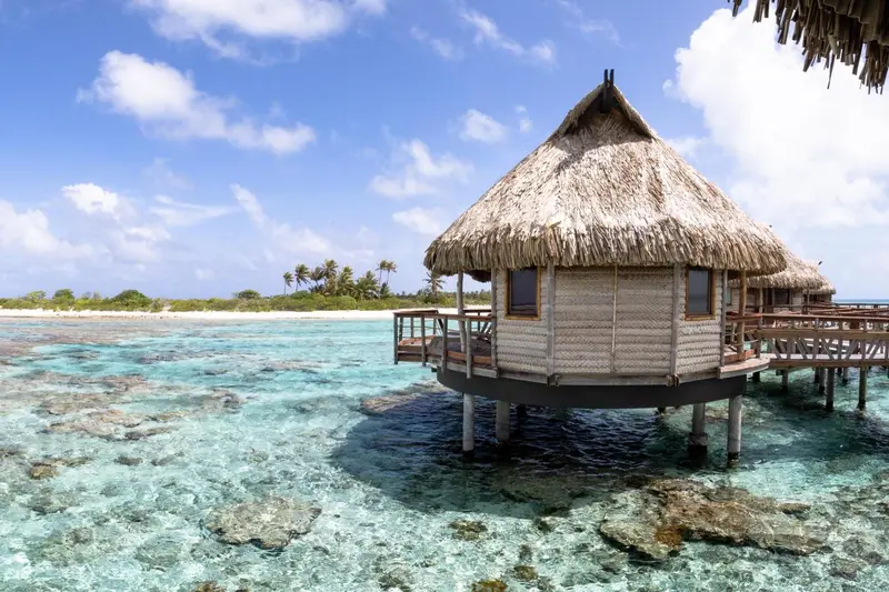 Maisons sur pilotis au-dessus d'un lagon turquoise sous un ciel bleu.