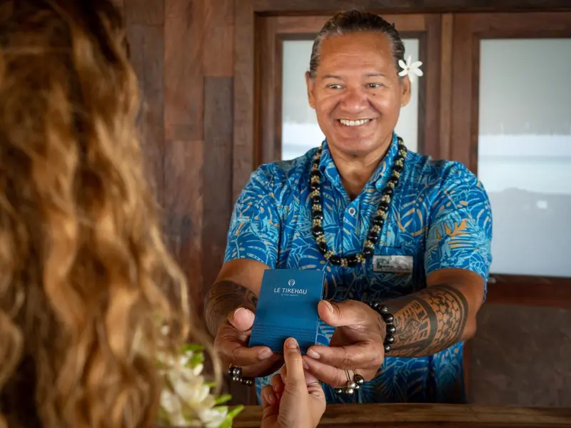 Un employé souriant tend une carte à un client.