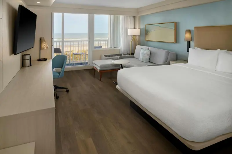Chambre lumineuse avec canapé et vue sur la mer.