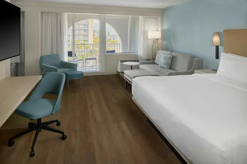 Chambre lumineuse avec canapé et bureau près d'une baie vitrée.